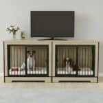 A modern, light wood double dog crate furniture console used as a TV stand, with a Jack Russell and a Cavalier King Charles Spaniel resting inside on white mats.
