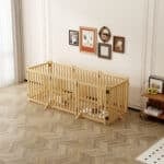 Light wood five-panel dog fence with vertical slats, enclosing a resting dog in a bright modern room with wall art and décor.